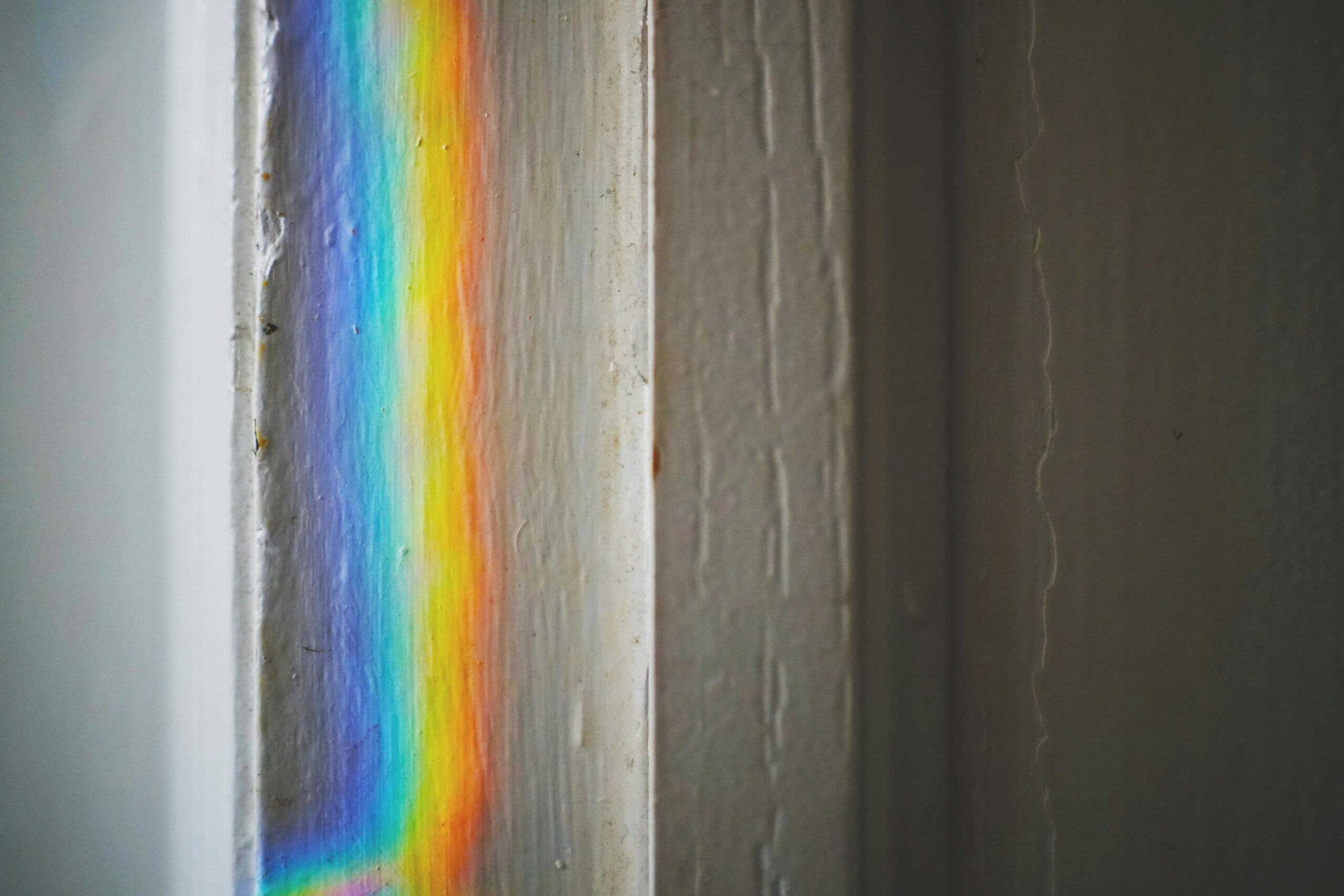 A white wooden wall with a vertical rainbow of light cast against it